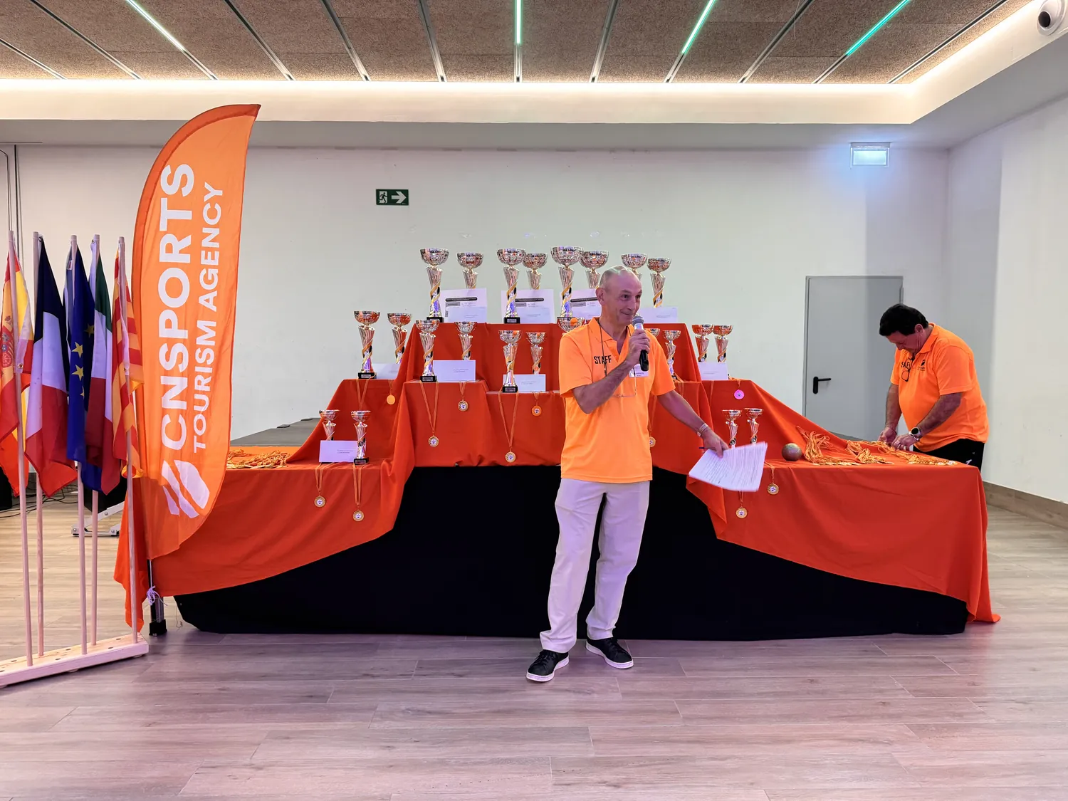 Organizador presentando la entrega de trofeos ante la mesa de copas de CN Sports